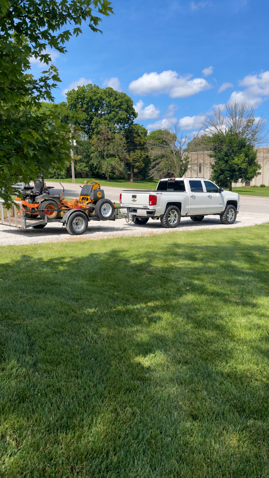 Our white pickup, utility trailer, and orange zero-turn mowers