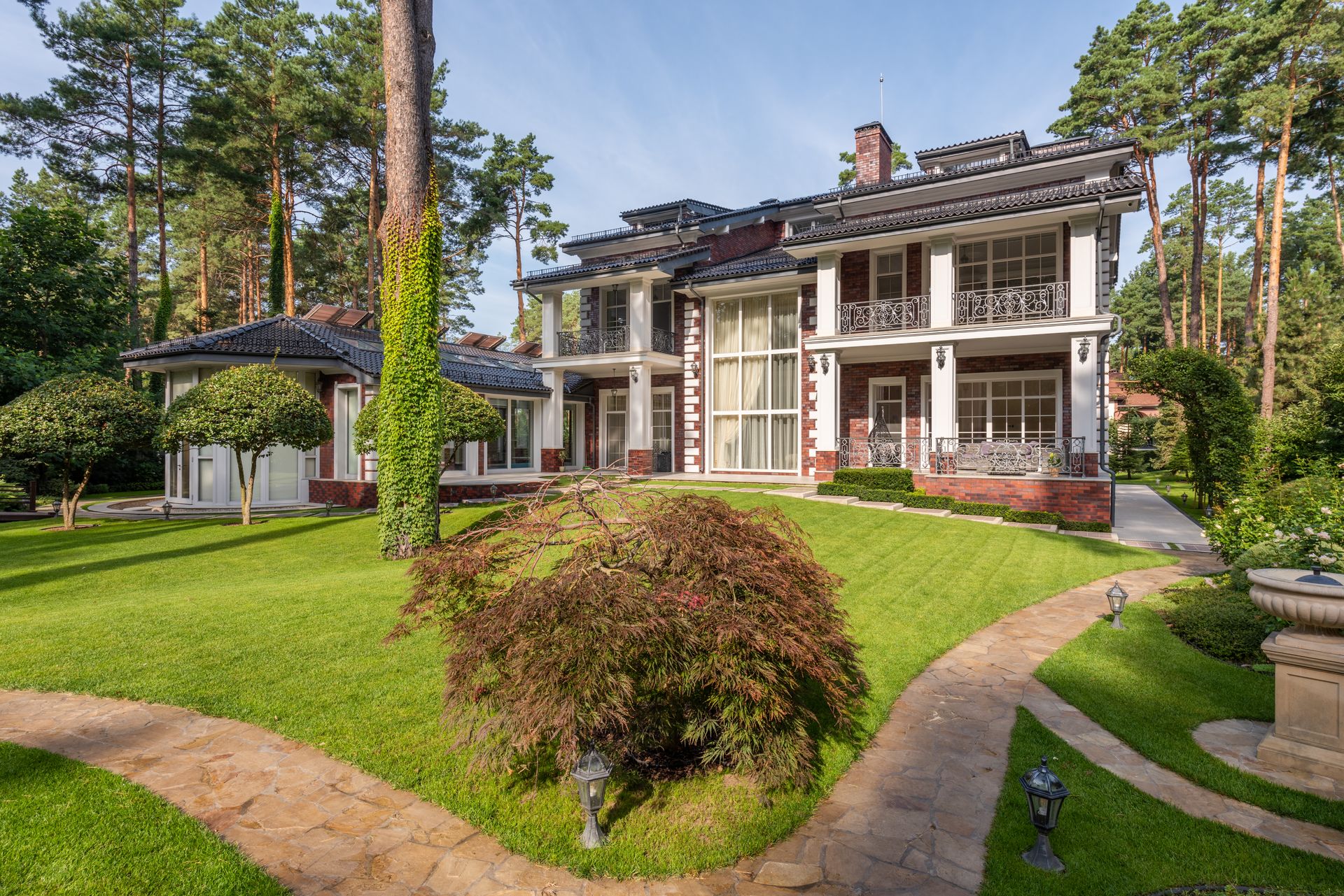 Stock landscaping photograph of a green lawn, ornamental shrubs, and stone pathways
